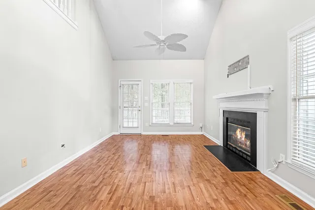 an empty room with wooden floor fireplace and windows