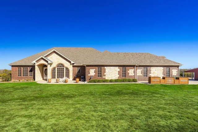 a view of a house with a big yard and large trees