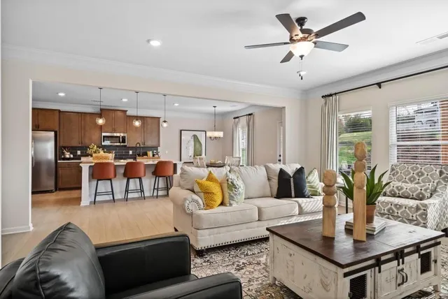 a kitchen with stainless steel appliances granite countertop a refrigerator a stove a kitchen island a dining table and chairs