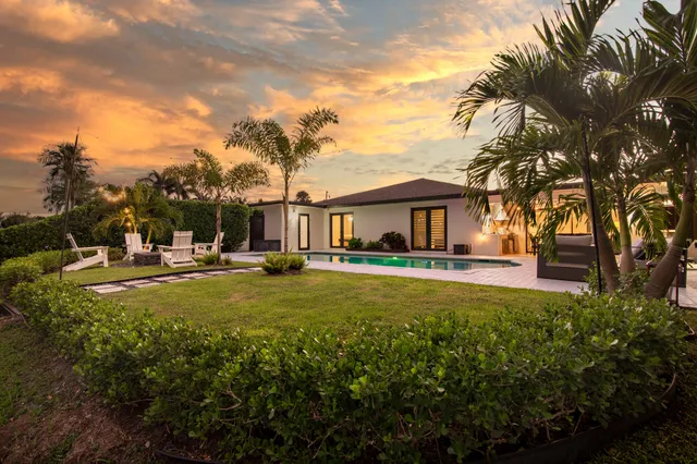 a front view of a house with garden and trees