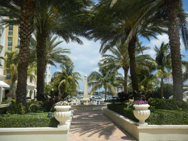 802 West Windward Way, Unit 211 Lantana, FL 33462 - Photo 10 of 32 a view of a white house with a fountain and potted plants and large trees