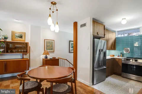 a kitchen with stainless steel appliances a refrigerator a sink dishwasher a dining table and chairs with wooden floor