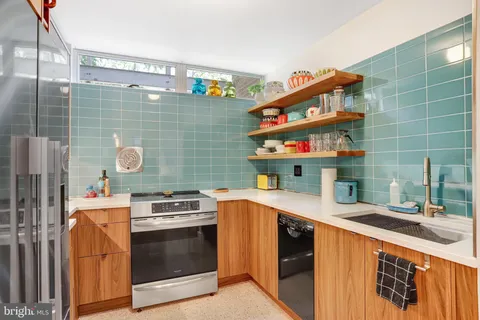a kitchen with stainless steel appliances granite countertop a sink and a stove next to a shower