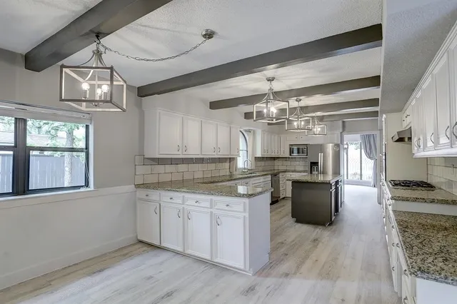 a kitchen with stainless steel appliances granite countertop a sink dishwasher a stove and white cabinets with wooden floor