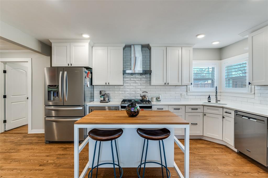 4245 Concho Street Dallas, TX 75206 - Photo 3 of 30 Kitchen with butcher block countertops, stainless steel appliances, white cabinetry, and a breakfast bar area