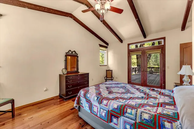 a bedroom with a bed next to a window with a flat tv screen