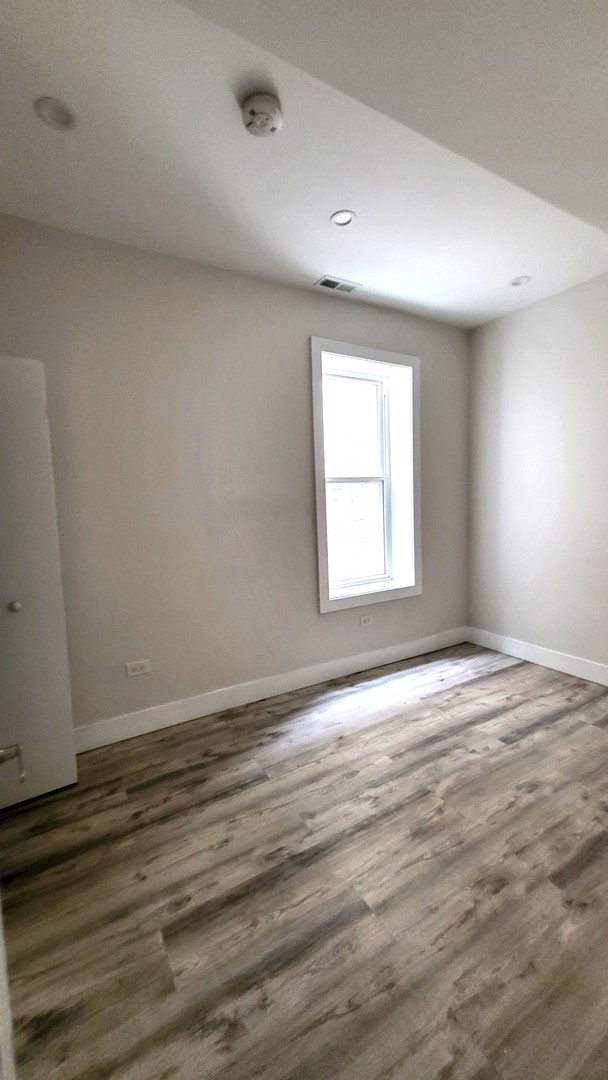 2904 West Nelson Street, Unit 2 Chicago, IL 60618 - Photo 12 of 12 an empty room with wooden floor and windows