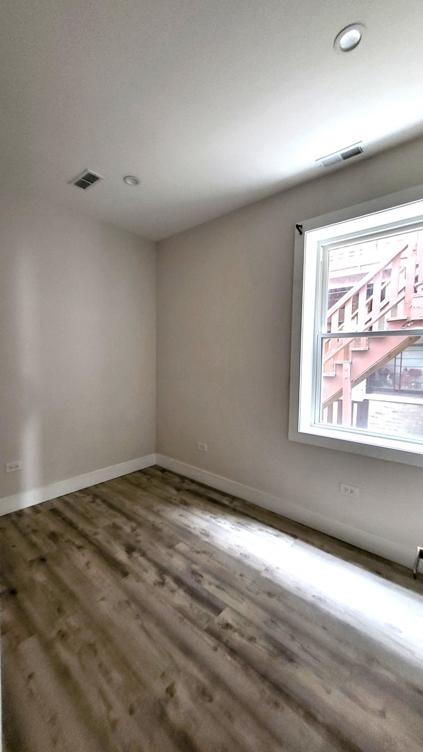2904 West Nelson Street, Unit 2 Chicago, IL 60618 - Photo 10 of 12 an empty room with wooden floor and windows