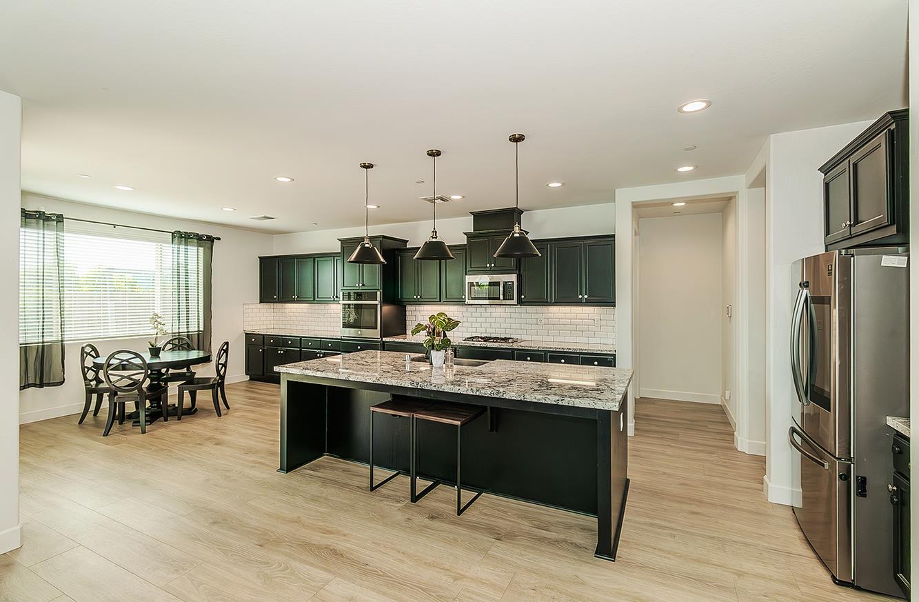 117 Emperor Way Dinuba, CA 93618 - Photo 12 of 32 a kitchen with stainless steel appliances kitchen island granite countertop a table chairs sink refrigerator and cabinets
