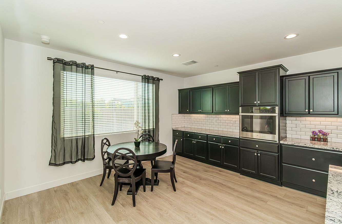 117 Emperor Way Dinuba, CA 93618 - Photo 13 of 32 a kitchen with stainless steel appliances wooden cabinets and dining table