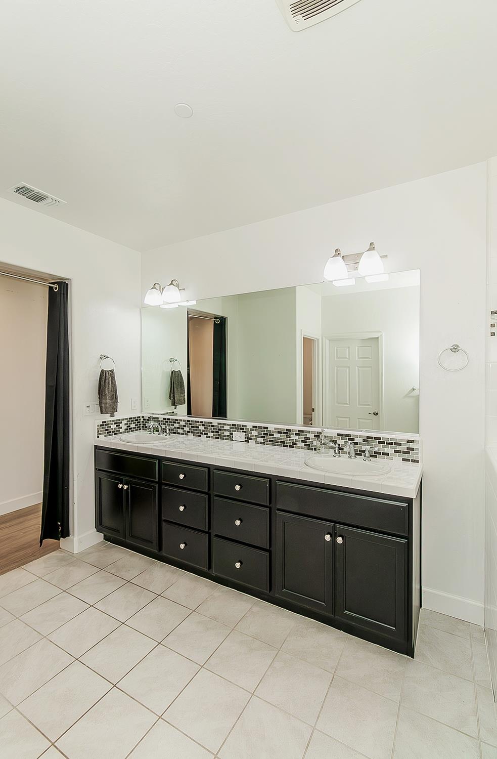 117 Emperor Way Dinuba, CA 93618 - Photo 24 of 32 a spacious bathroom with a granite countertop double vanity and a mirror
