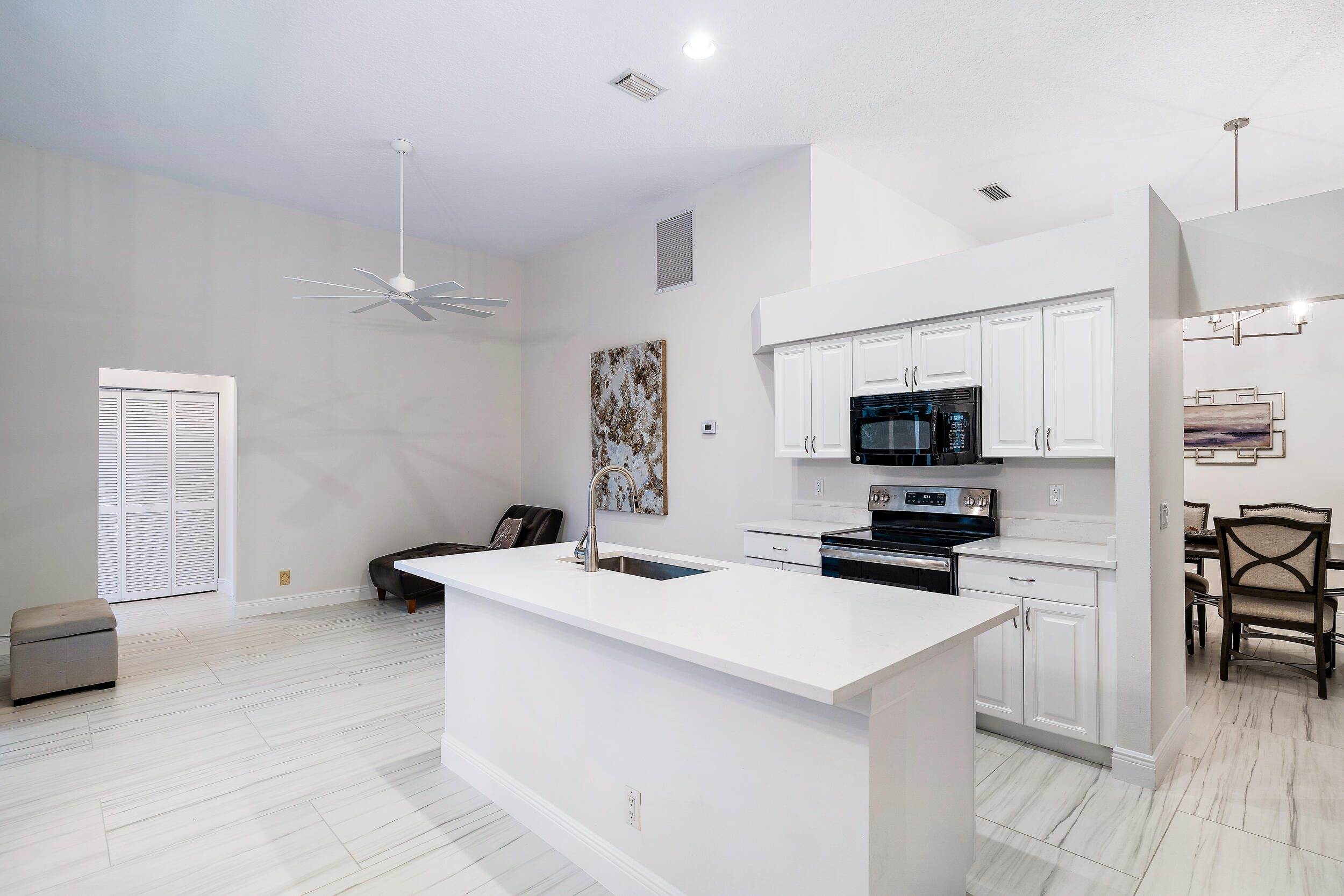 207 Eagleton Estates Boulevard Palm Beach Gardens, FL 33418 - Photo 14 of 34 a kitchen that has a sink a microwave oven a stove and white cabinets with wooden floor