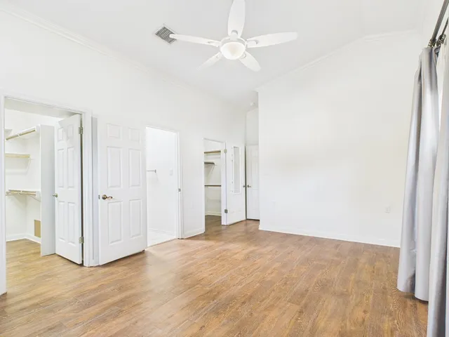 an empty room with wooden floor and ceiling fan