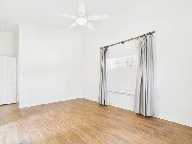 an empty room with wooden floor closet and fan