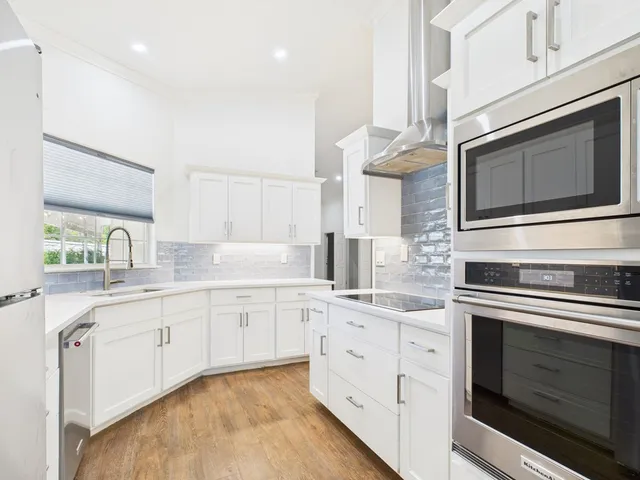 a kitchen with stainless steel appliances granite countertop a stove and white cabinets