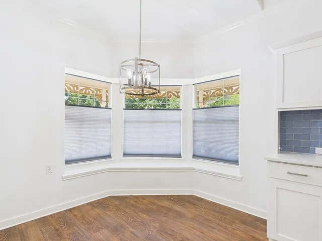 a view of empty room with wooden floor and kitchen
