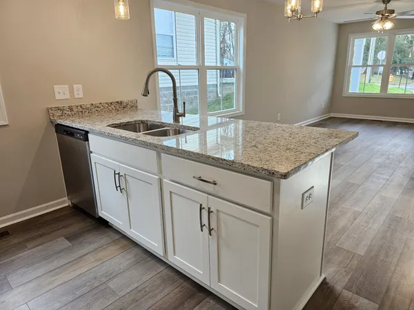 a kitchen with granite countertop white cabinets and a wooden floor
