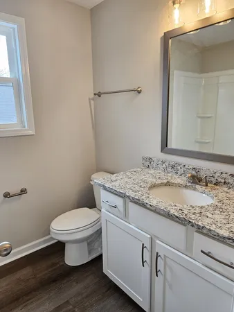 a bathroom with a granite countertop toilet sink and mirror