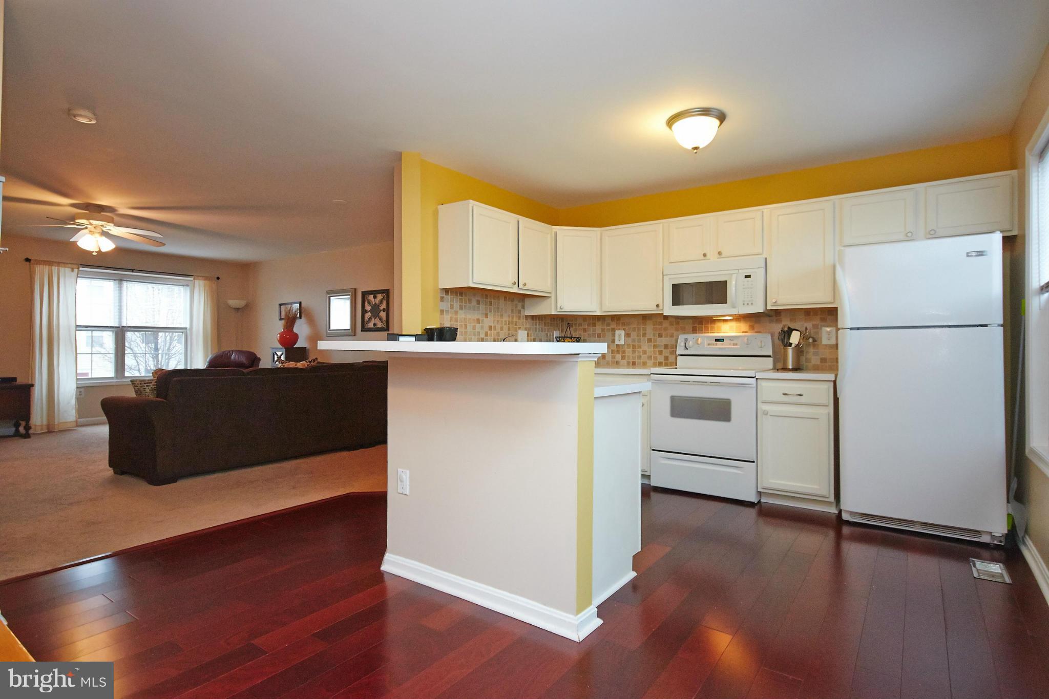 8461 Tackhouse Loop Gainesville, VA 20155 - Photo 8 of 29 a kitchen with a refrigerator a stove top oven a sink dishwasher and white cabinets with wooden floor