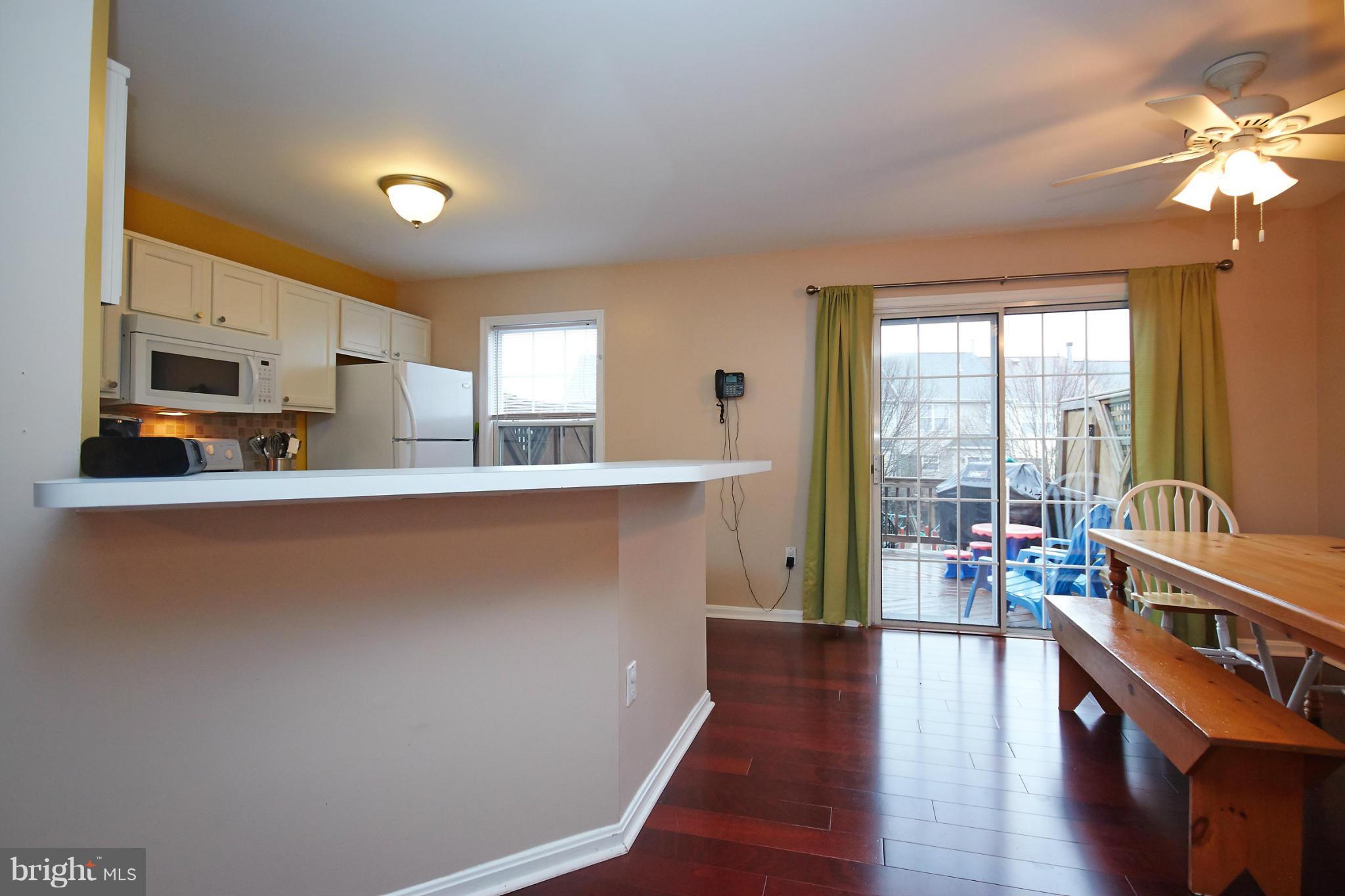 8461 Tackhouse Loop Gainesville, VA 20155 - Photo 9 of 29 a kitchen with stainless steel appliances a large counter top a stove a chimney a sink and dishwasher a refrigerator with wooden floor