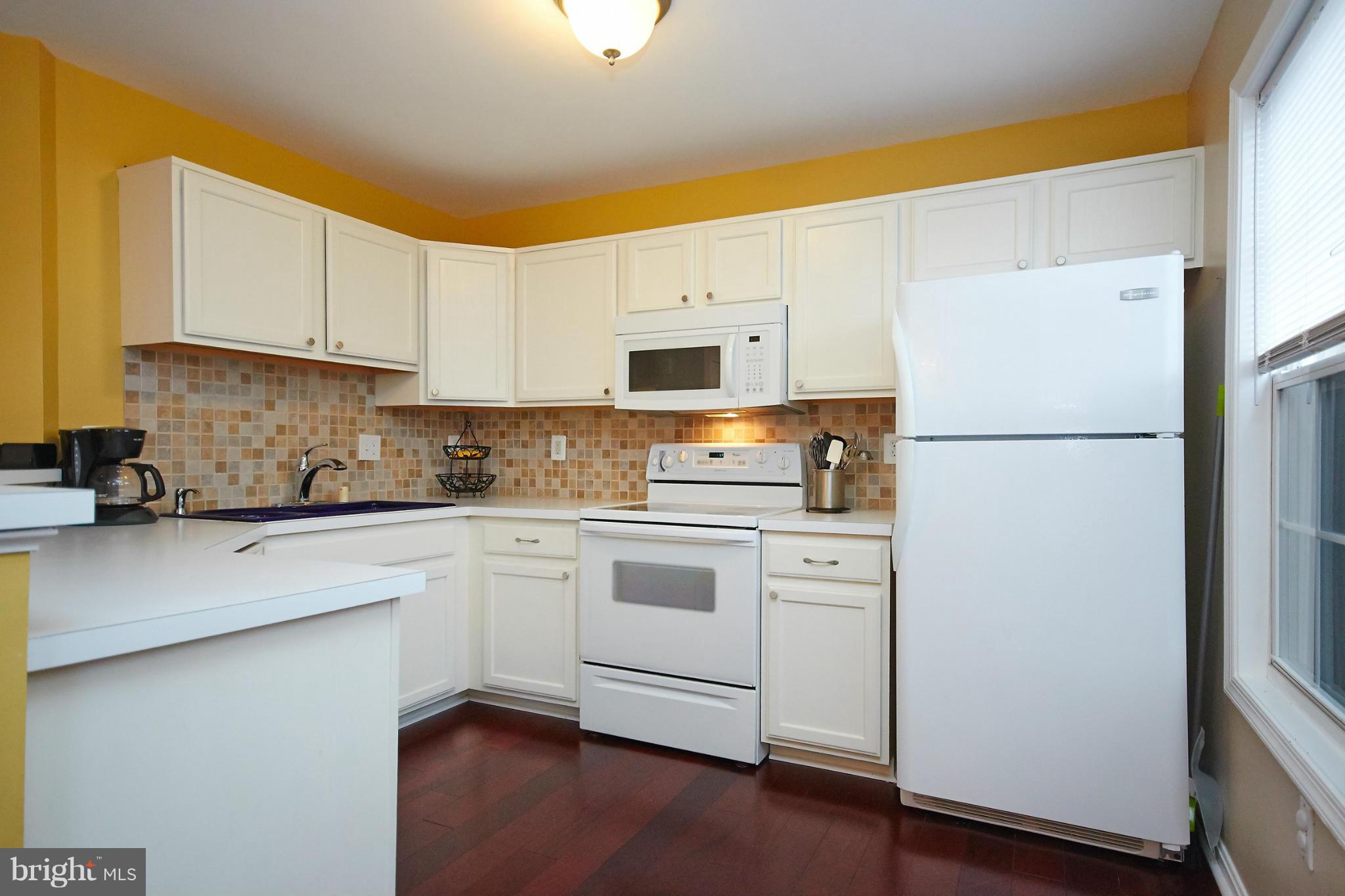 8461 Tackhouse Loop Gainesville, VA 20155 - Photo 10 of 29 a kitchen with white cabinets and white appliances