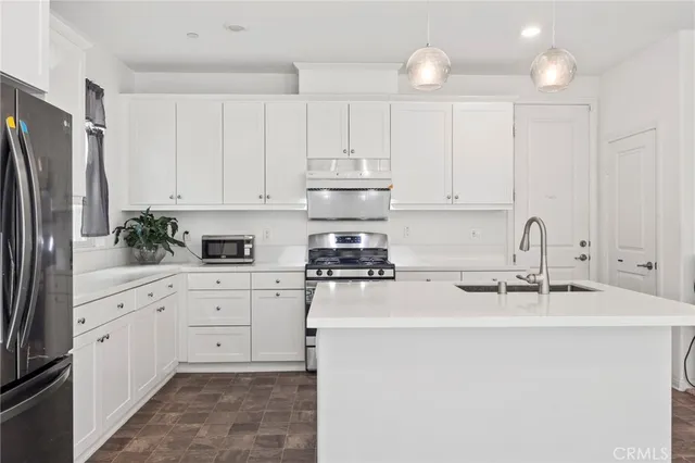 a kitchen with stainless steel appliances granite countertop a refrigerator sink and white cabinets