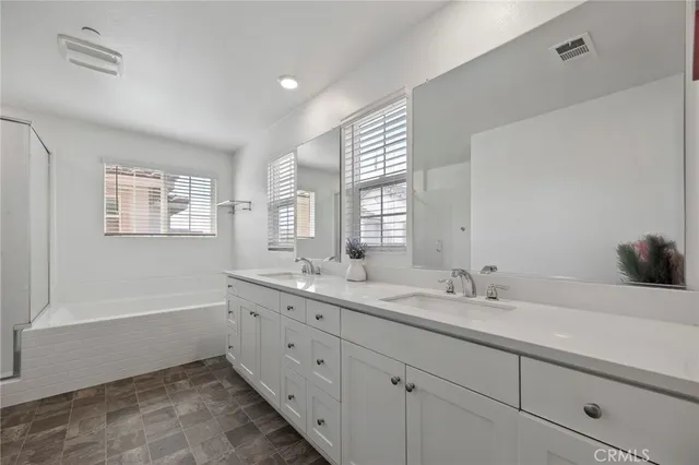 a bathroom with a double vanity sink a mirror and a bathtub