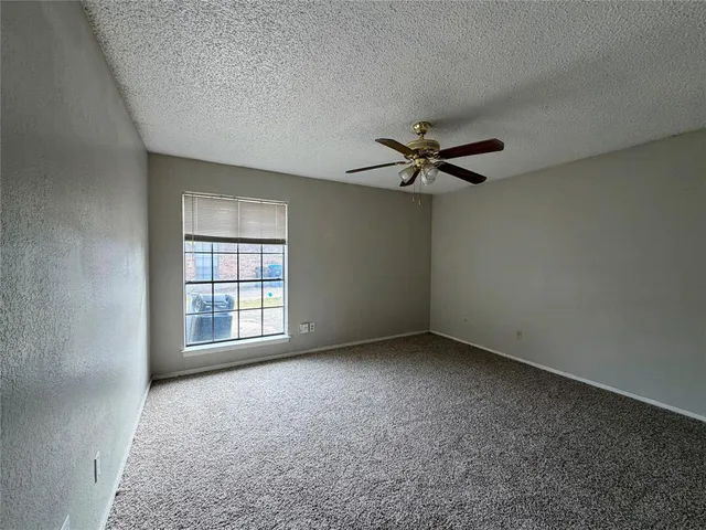 an empty room with a window and a ceiling fan