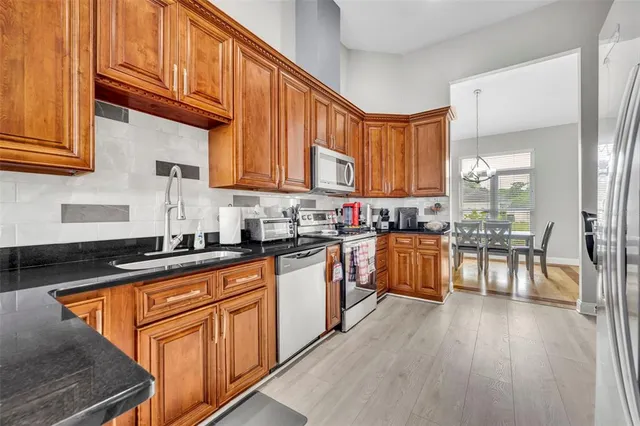 a kitchen with stainless steel appliances granite countertop wooden cabinets a sink and dishwasher a stove with wooden floor