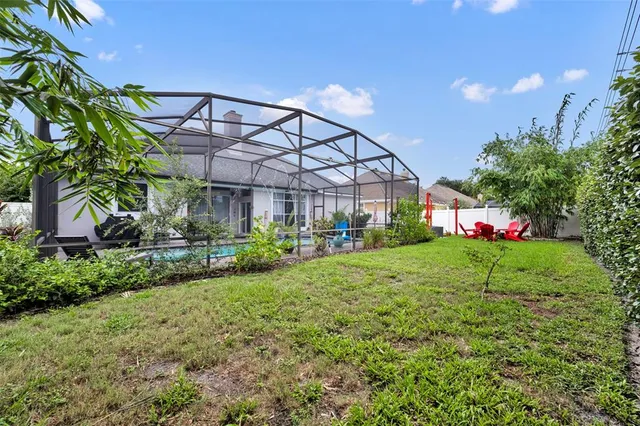a yellow and red house with a big yard and potted plants
