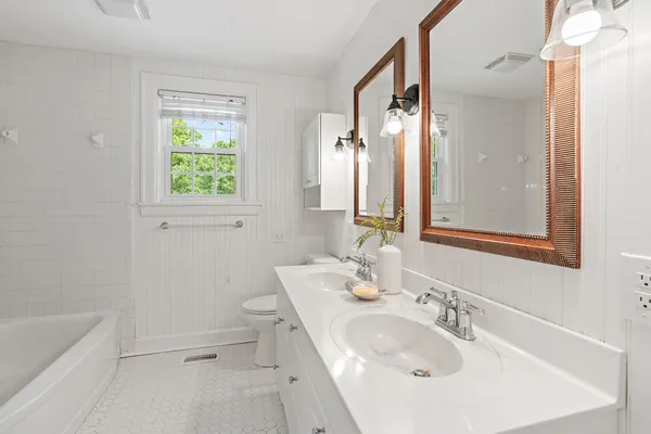 a bathroom with a tub sink and mirror