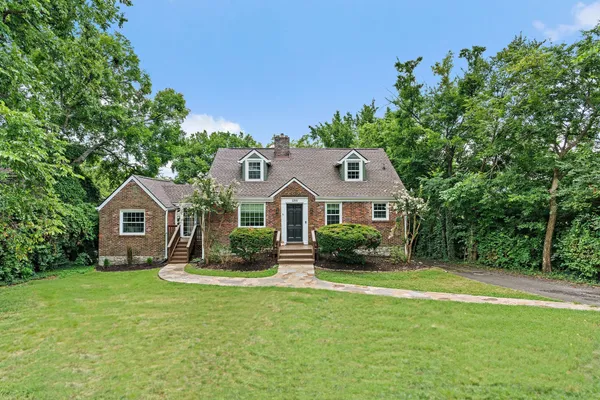 a front view of a house with a garden and trees