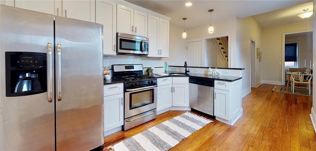 1321 Reddour Street Pittsburgh, PA 15212 - Photo 6 of 21 a kitchen with stainless steel appliances a stove a refrigerator a sink a stove and white cabinets with wooden floor