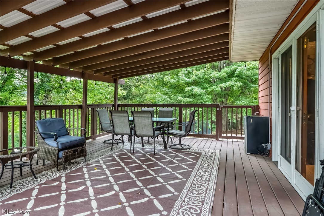 4922 South Ridge Road East Geneva, OH 44041 - Photo 31 of 46 Secondary perspective of the spacious covered deck, highlighting the tranquil wooded backdrop and direct entry into the home.