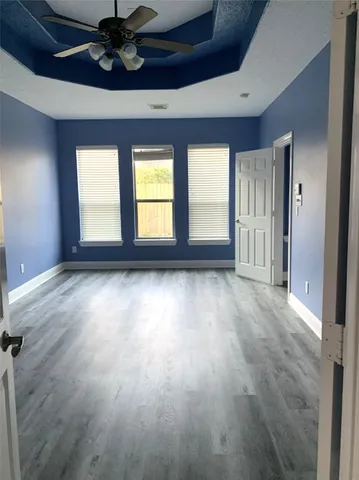 a view of empty room with wooden floor and fan