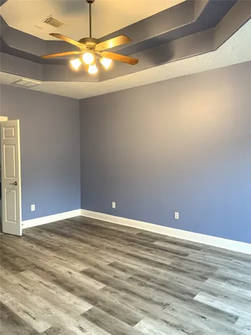 a view of an empty room with window and chandelier fan