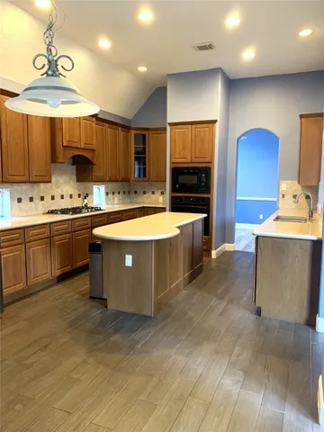 a large kitchen with a large counter top a sink stainless steel appliances and cabinets