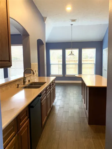 a large kitchen with kitchen island a large window a sink and stainless steel appliances