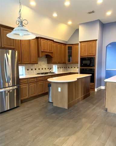 a kitchen with stainless steel appliances granite countertop a sink counter space cabinets and a refrigerator