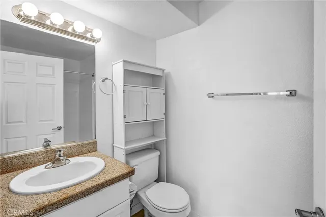 a bathroom with a granite countertop sink toilet a mirror and shower