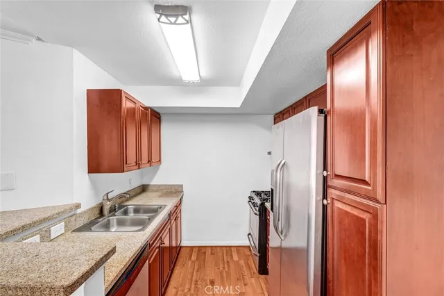 a kitchen with stainless steel appliances granite countertop a refrigerator a sink and wooden cabinets