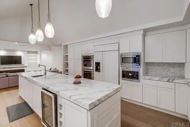 a kitchen with a stove a sink dishwasher and a flat screen tv