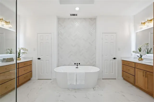 a spacious bathroom with a double vanity sink a mirror and a bathtub