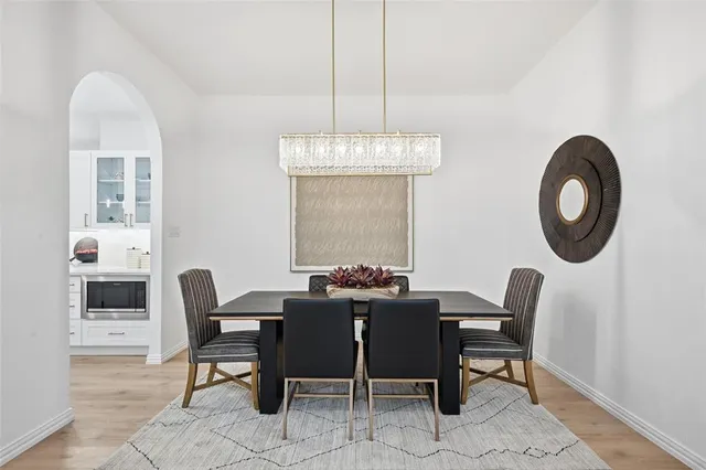 a dining room with chandelier fan and wooden floor