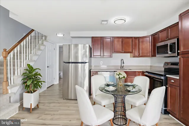 a kitchen with stainless steel appliances granite countertop a refrigerator a stove a sink cabinetry and dining table