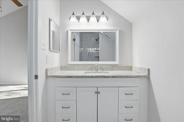 a bathroom with a granite countertop sink and two mirror