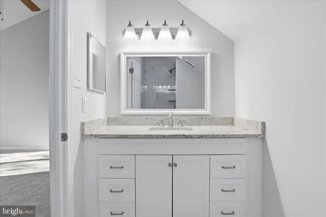 a bathroom with a granite countertop sink and two mirror