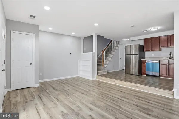 a view of a electric appliances in kitchen and an empty room with wooden floor
