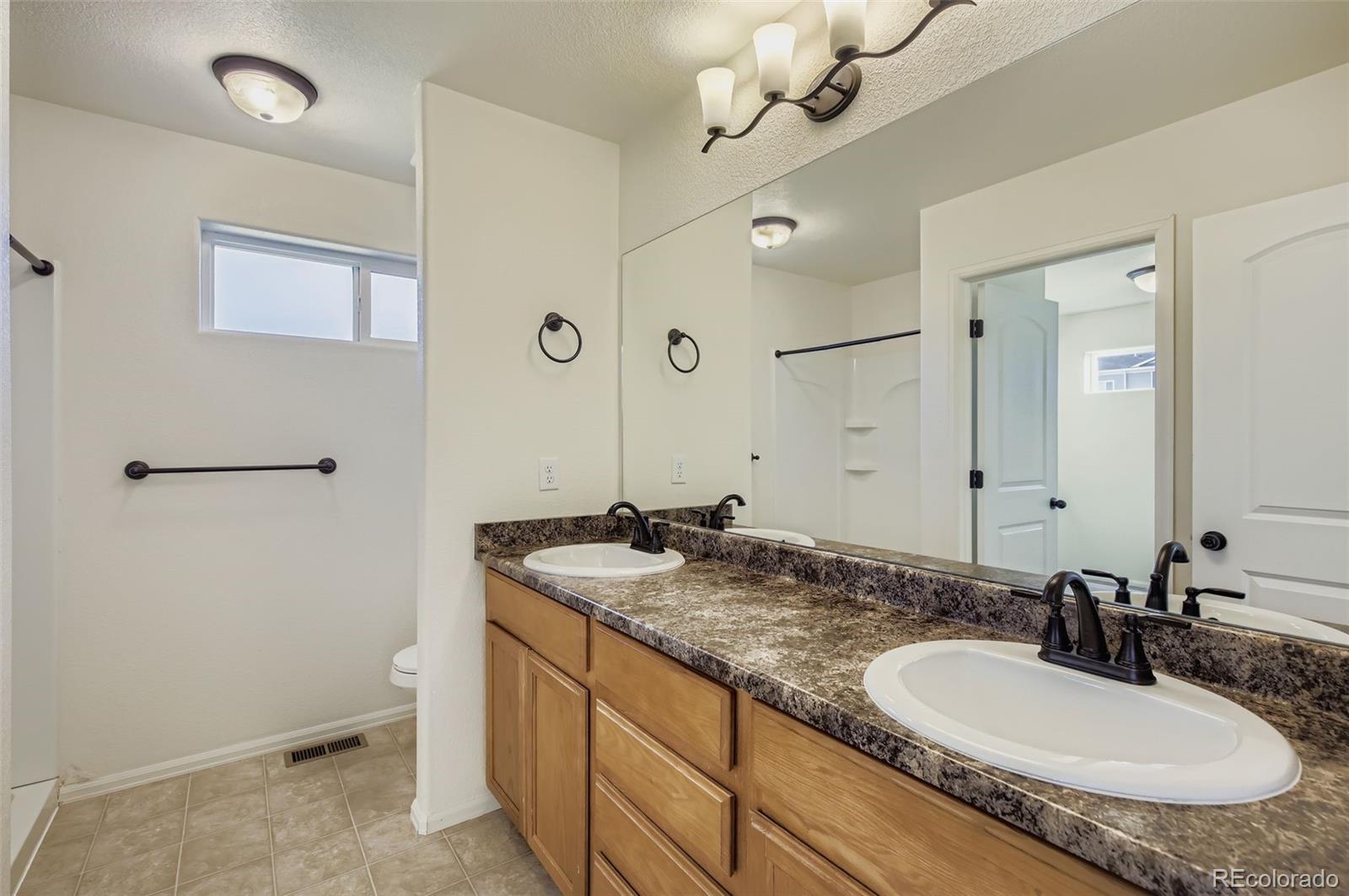 10300 19th St Road Greeley, CO 80634 - Photo 17 of 33 a bathroom with a granite countertop sink a mirror and a shower