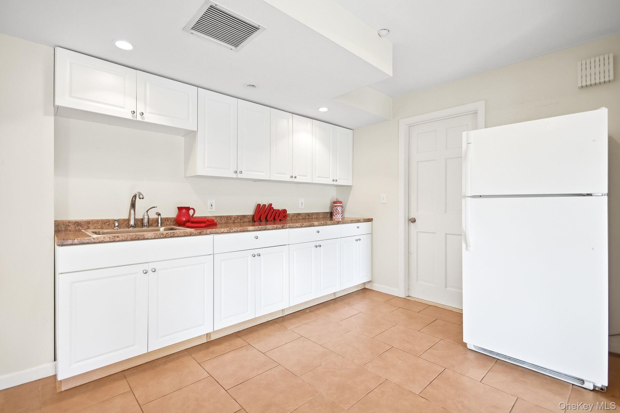 26 Century Ridge Road Purchase, NY 10577 - Photo 32 of 50 Kitchenette featuring white cabinetry, light-toned countertops, a stainless steel sink, and tile flooring